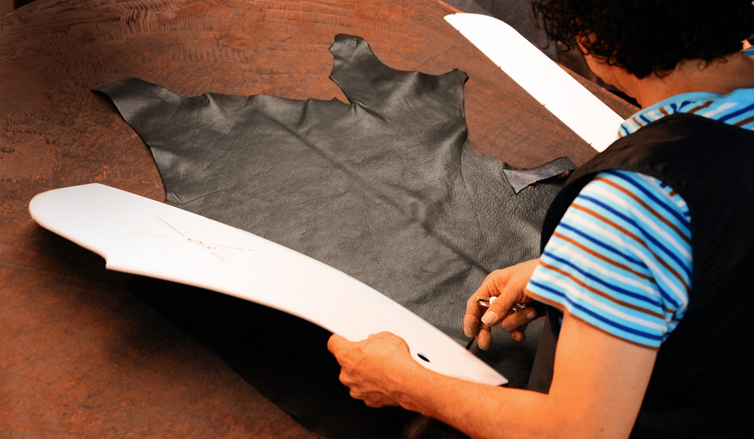 Woman is cutting leather using a pattern